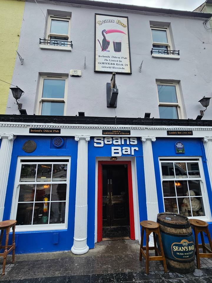 Exterior of a local bar with signage and human figures.