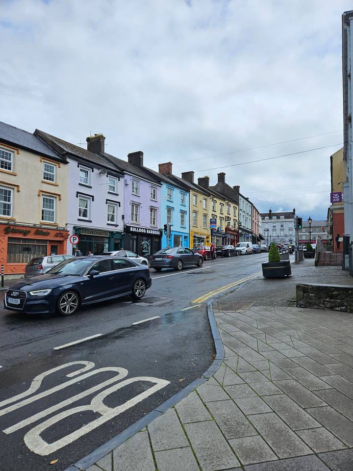 Pedestrian street with colorful buildings and parked cars.