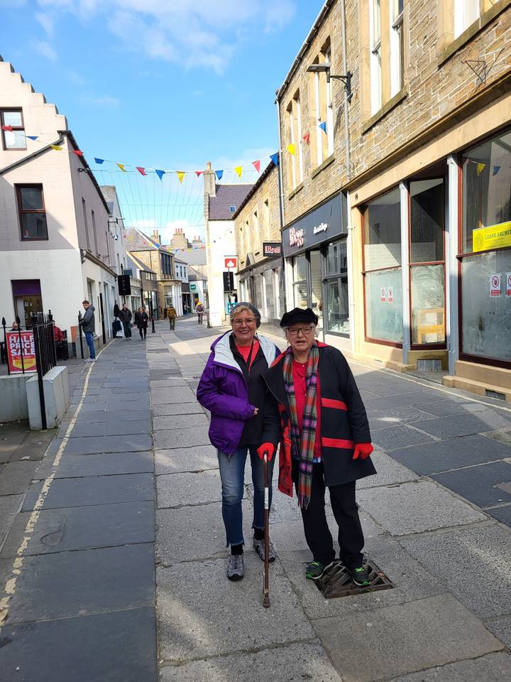 Two people walking down a street in a Scottish town.