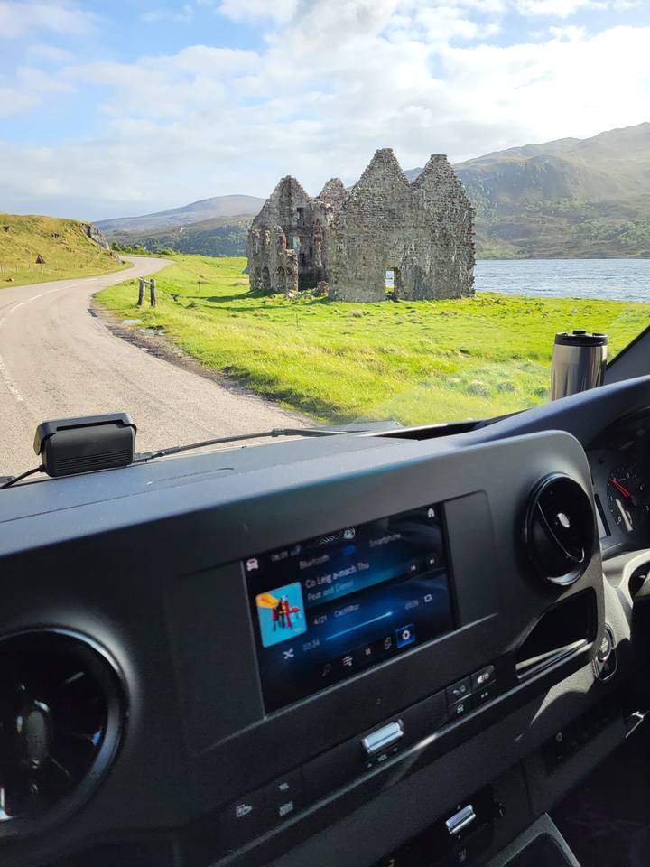 A view of a castle ruin from inside a car.