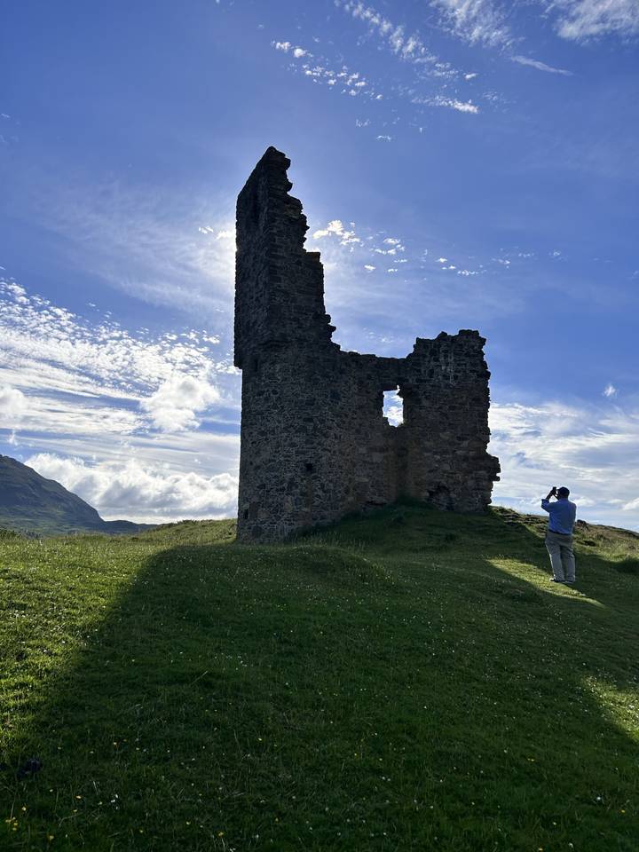 Ruins of a stone tower in a grassy landscape