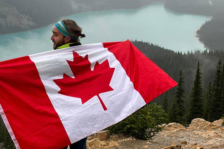Traveller with Canadian flag overlooking the Rockies