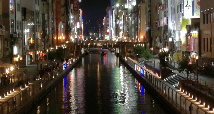 Canal éclairé avec des reflets de lumières la nuit.