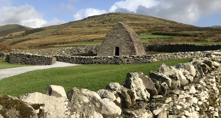 Stenen gebouw met een kegelvormig dak in een weelderig groene omgeving.