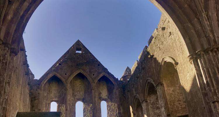 Interieur van een vervallen stenen gebouw met gotische bogen.