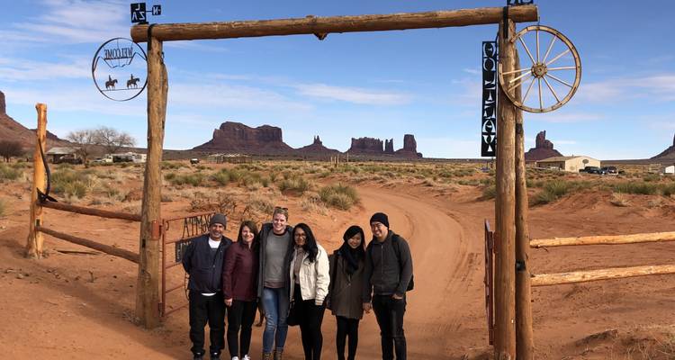 Gruppe von Menschen, die unter einem Ranchtor mit Felsformationen im Hintergrund posieren.