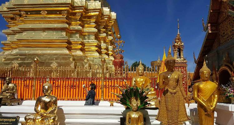 Golden statues and a temple complex under a blue sky.
