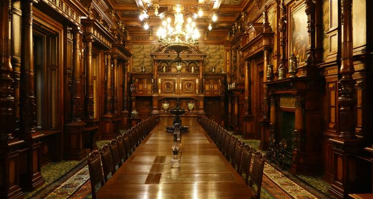 Luxuriöser Palast-Speisesaal mit kunstvollen Holzarbeiten und Kronleuchtern.