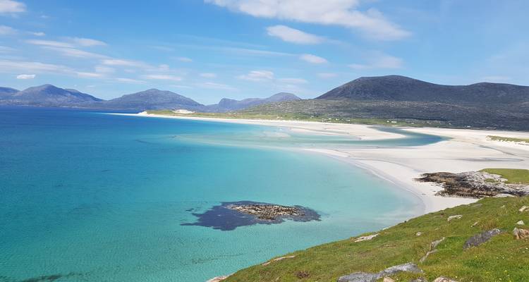 Vista amplia de playa prístina con aguas verde-azuladas.