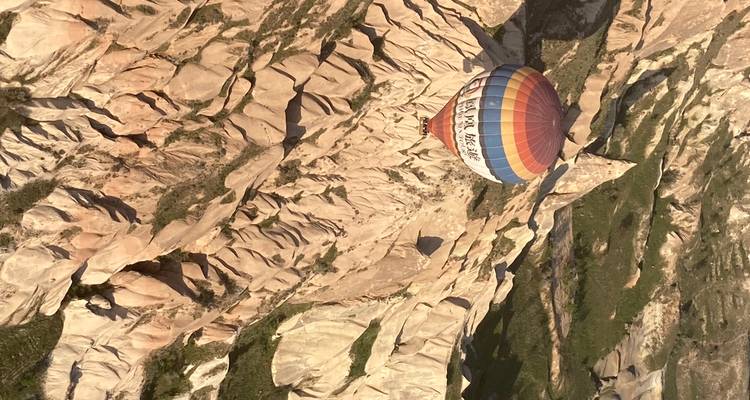 Hot air balloon flying over a rocky landscape.