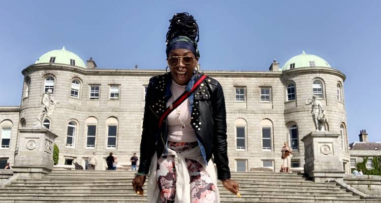 Persoon die poseert voor een historisch gebouw met stenen trappen.