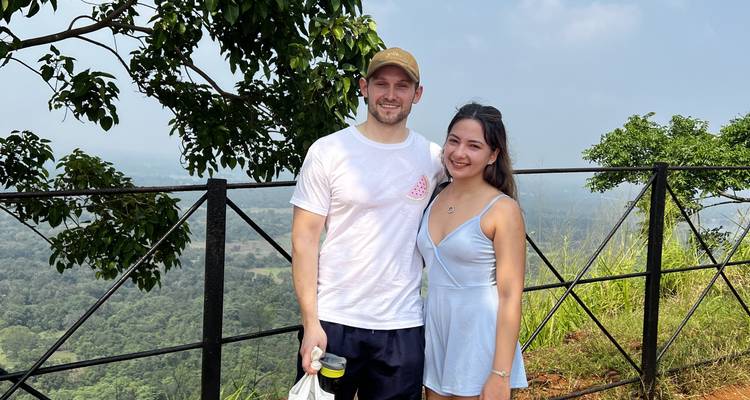 Couple souriant avec un paysage vallonné en arrière-plan.