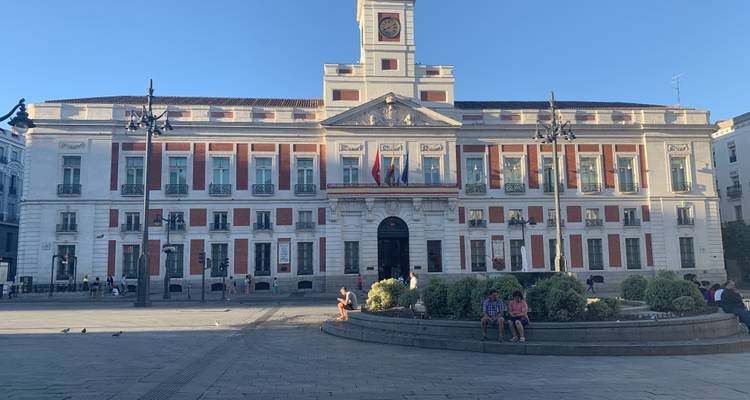Gran edificio gubernamental con banderas y un cielo azul despejado.