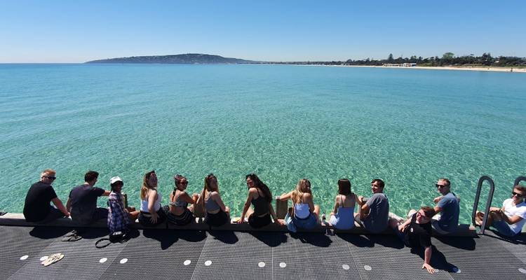Des gens assis sur un quai avec de l'eau claire.
