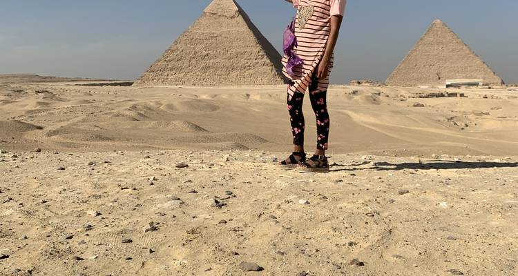 Person standing in front of the pyramids in Giza.