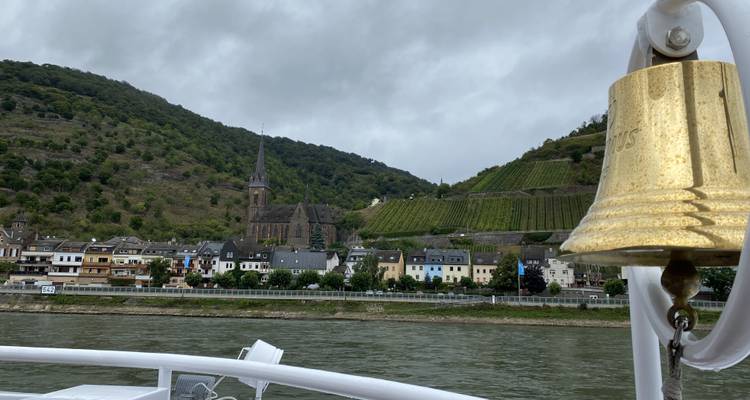 A ship's bell with a vineyard and village scenery by a river.