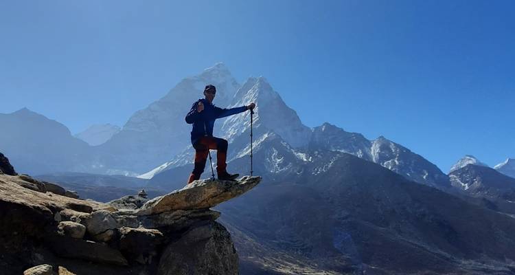 Wandelaar poseert op de top van een piek met besneeuwde bergen.