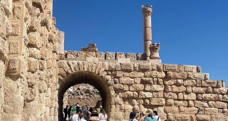 Touristes sur un site archéologique antique avec des arches.