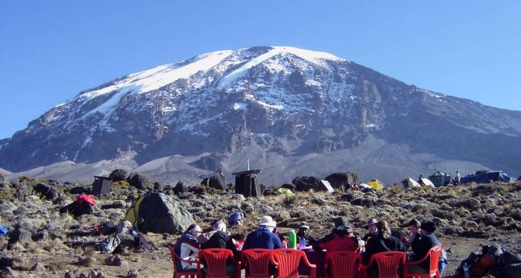 Des gens qui dînent avec une montagne enneigée en arrière-plan.