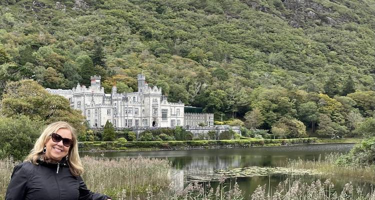 Vrouw die poseert voor een schilderachtig kasteel met groen.