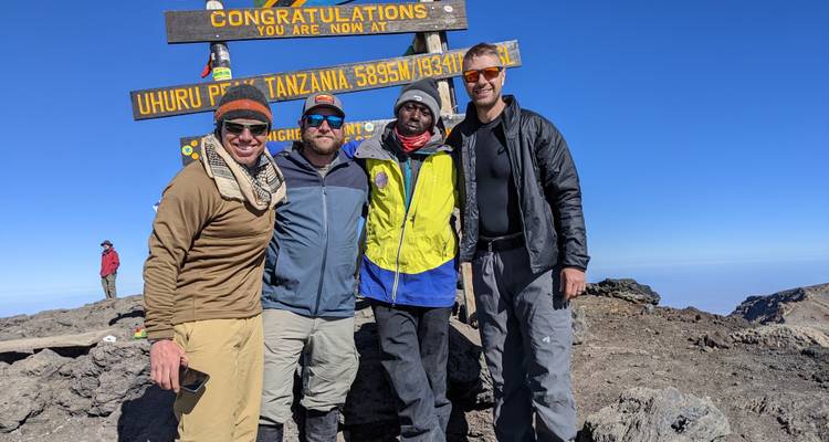 Grupo de personas en el Pico Uhuru, letrero de la cumbre del Kilimanjaro.