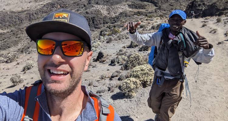 Dos hombres caminando con equipo en un área rocosa.