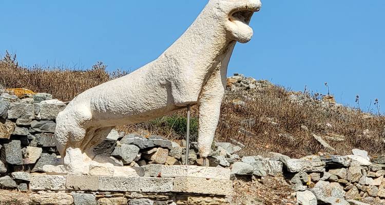 Ancient stone statue of a lion in an open field.