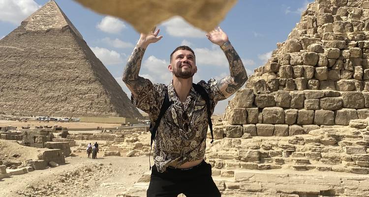 Una persona posando cerca de las pirámides con un gesto juguetón.