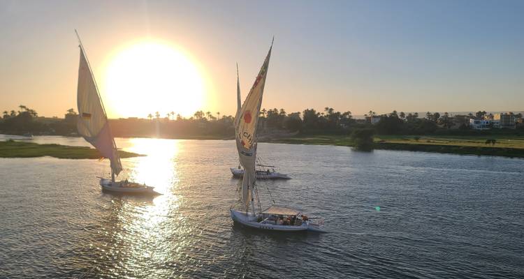 Zeilboten op een rivier tijdens zonsondergang.
