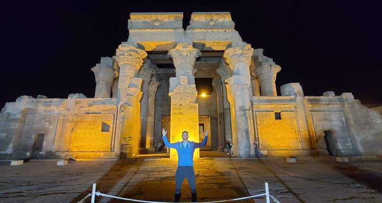 Man die poseert voor een verlichte oude tempel in de nacht.