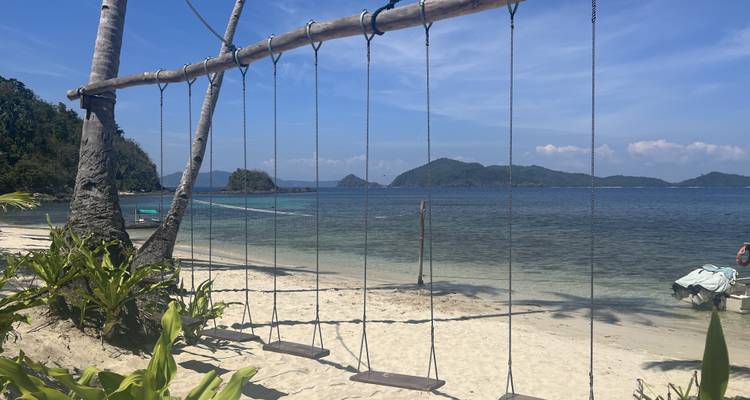 Vue sur le front de mer avec des balançoires et une eau bleue claire.