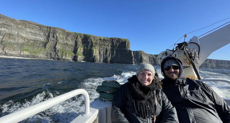 Twee mensen op een boot met kliffen op de achtergrond.