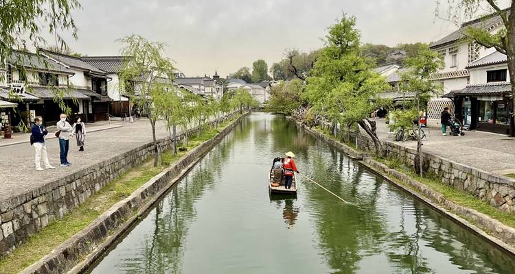 Un canal qui traverse une ville japonaise historique avec des gens sur un bateau.