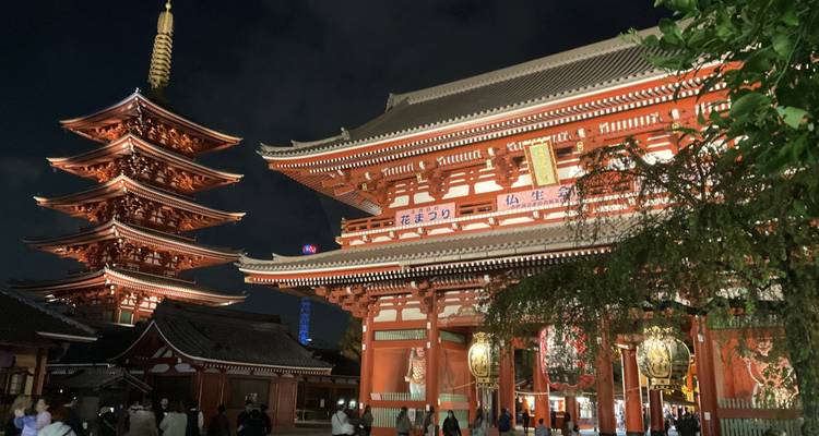 Temple et pagode de Sensō-ji illuminés la nuit avec des visiteurs au premier plan.