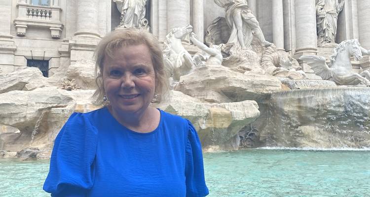 Personne debout près de la fontaine de Trevi avec une architecture baroque en arrière-plan.