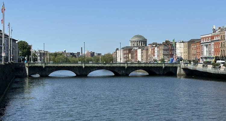 River with a stone bridge and classical building in Dublin.