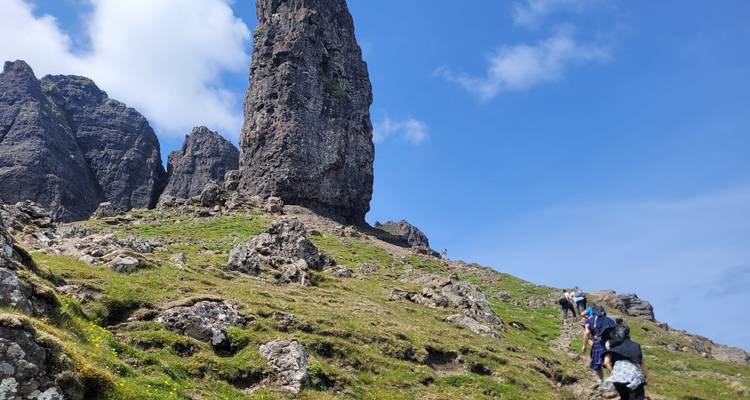 People hiking towards rugged rock formations.