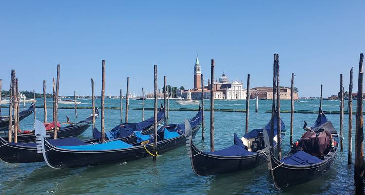 Des gondoles amarrées dans un canal avec une église en arrière-plan.