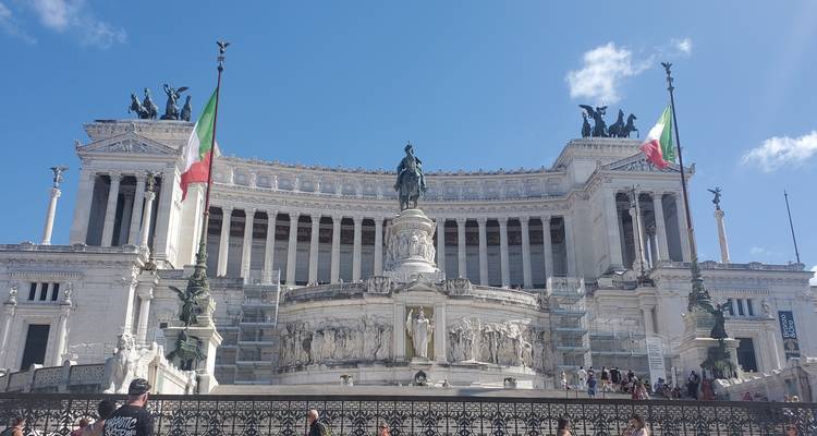 Bâtiment monumental avec colonnes et drapeaux italiens.