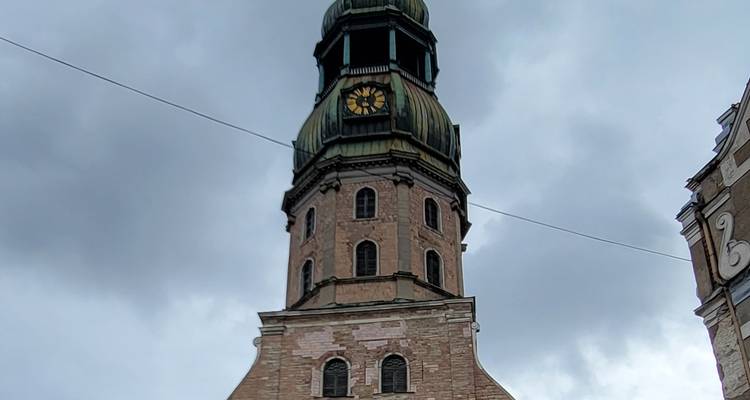 Ein Uhrenturm mit einem Kuppeldach vor einem bewölkten Himmel.
