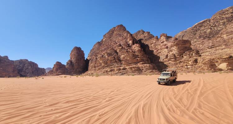 Un jeep conduciendo a través de un paisaje desértico con formaciones rocosas rojas.