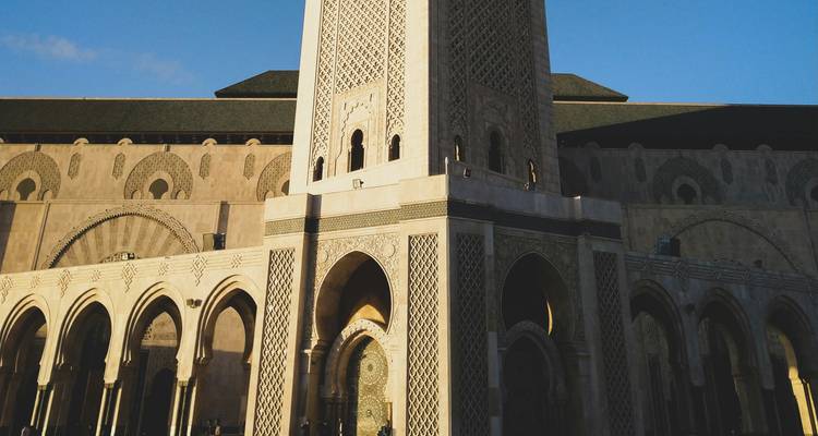 Grand minaret d'une mosquée contre un ciel bleu.