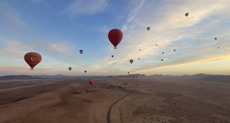 Montgolfières volant au-dessus d'un vaste paysage désertique.
