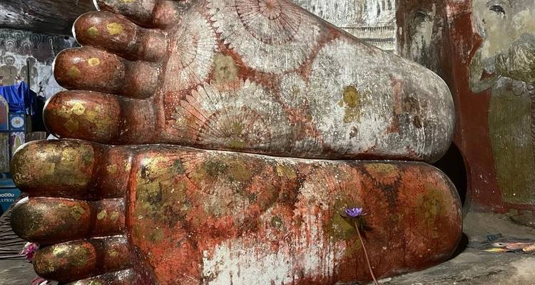 Grande statue aux pieds ornementés à l'intérieur d'une grotte.