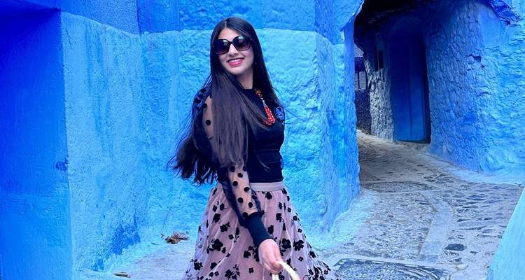 Woman walking down a narrow blue alley.