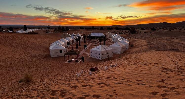 Desert camp with tents at sunset.