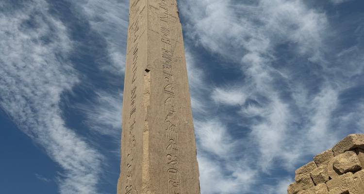 Grand obélisque de pierre avec des inscriptions sous un ciel dégagé.