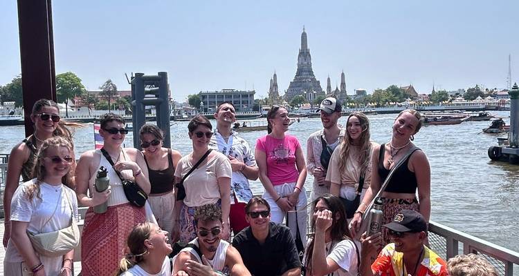 Grupo de turistas con un río y templo de fondo.