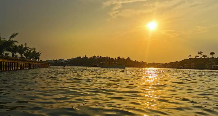 Sunset over a body of water with a boat in the distance.