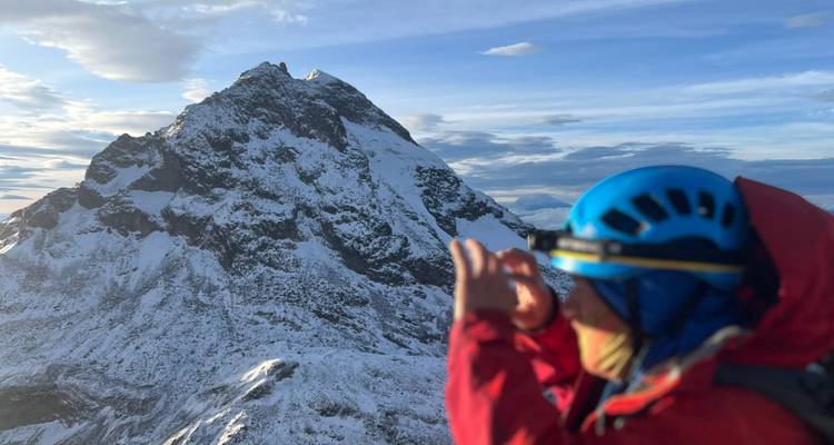 Alpiniste prenant une photo d'un sommet enneigé.